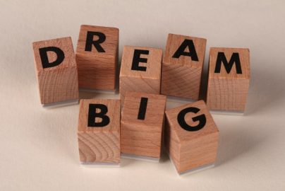 Inspiring arrangement of wooden blocks spelling 'Dream Big' on a neutral beige background.