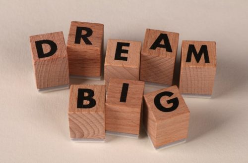 Inspiring arrangement of wooden blocks spelling 'Dream Big' on a neutral beige background.