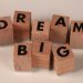 Inspiring arrangement of wooden blocks spelling 'Dream Big' on a neutral beige background.
